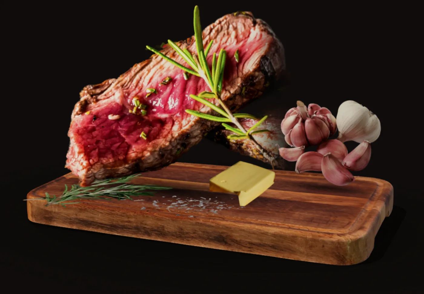 Medium-rare ribeye slices on a wooden board with a pat of butter, rosemary, pink garlic and sea salt flakes